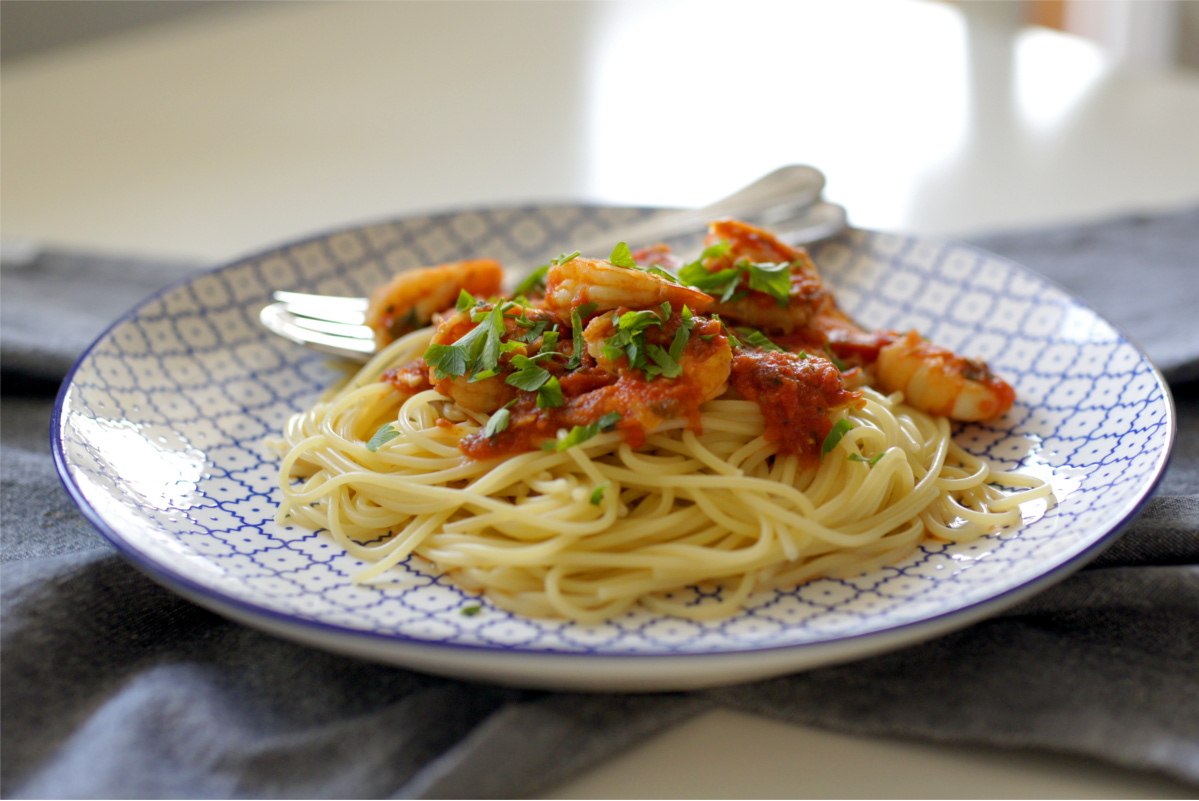 krewetki w sosie pomidorowym z makaronem spaghetti na talerzu 