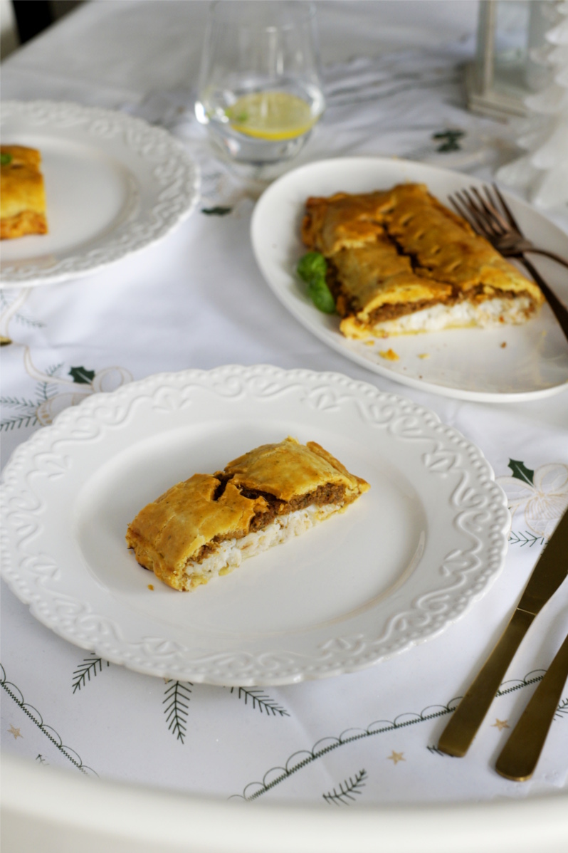 halibut w kruchym cieście z pesto pomidorowym leży na świątecznym stole, białe talerze, biały półmisek